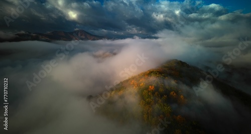 Fototapeta Naklejka Na Ścianę i Meble -  a big mountain covered in a lot of mist under a cloudy sky