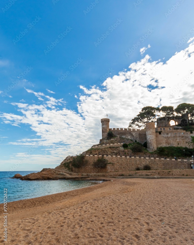 Old castle on a rocky hill on the tropical beach with white sands in Tossa De Mar
