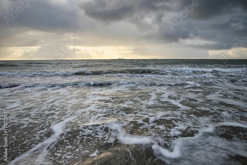 Beach scene featuring a serene sunset with waves rolling in on the sandy shore  Isle of Wight