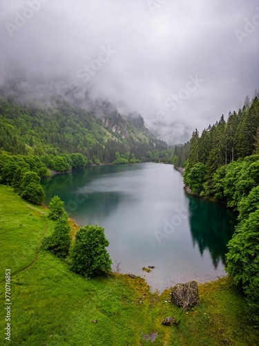 Scenic view of Lake Susica surrounded by cloudy mountains photo