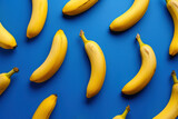 Fresh ripe bananas on vibrant blue background, arranged in a flat lay composition, top view perspective