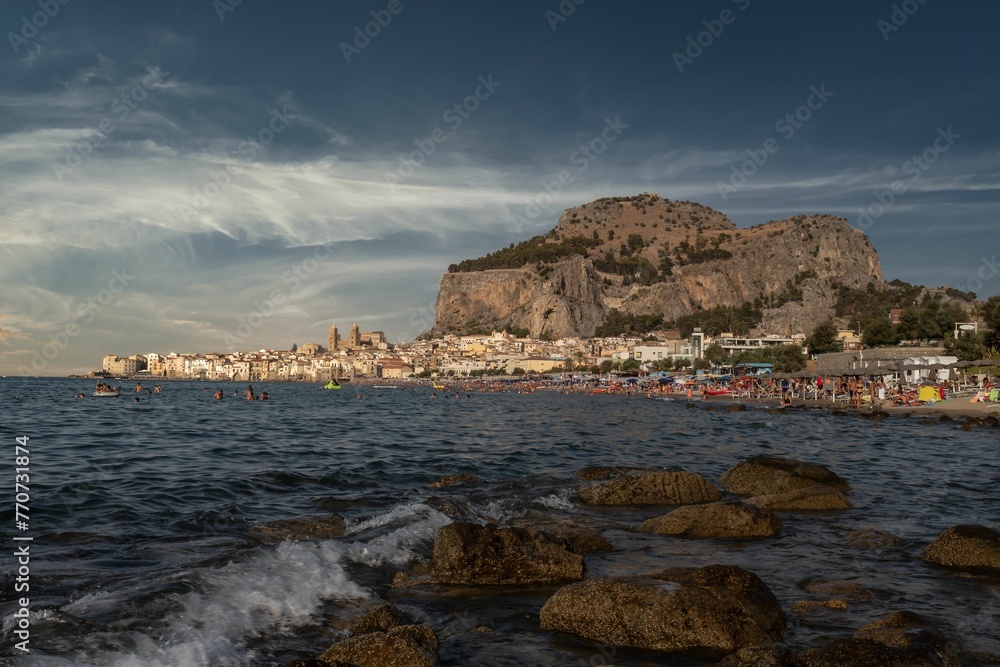 Scenic view of the coastline featuring cliffs and buildings in Cefalu, Italy