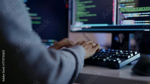 A close-up shot of a programmer's hands on a mechanical keyboard, coding late at night with focused precision on multiple screens.