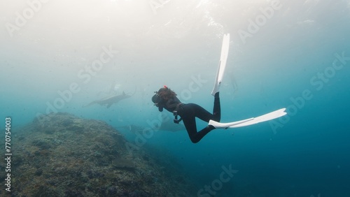 Underwater photographer takes picture of manta ray. Freediver with camera films Giant ocean Manta Ray swimming over reef. Nusa Penida, Bali, Indonesia © Dudarev Mikhail