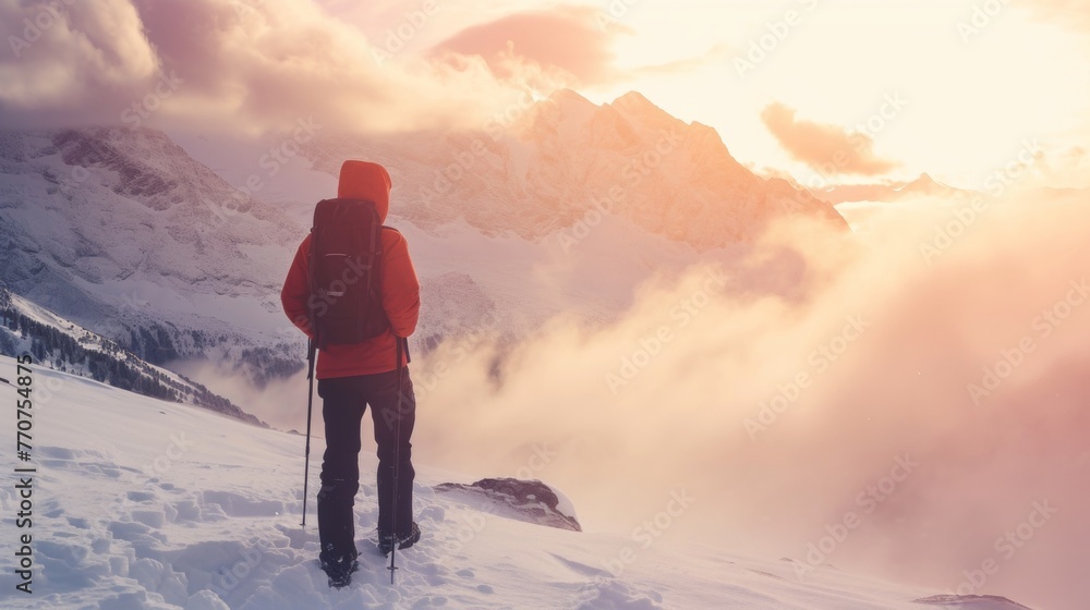Hiker standing on tip of mountain top in winter in rugged lands with snow and majestic view.
