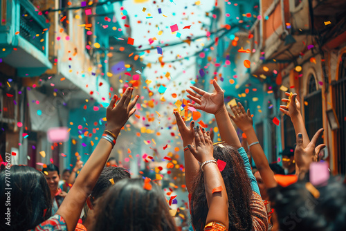 Back view of a person with raised hands, celebrating with a crowd under a shower of confetti on a vibrant city street.