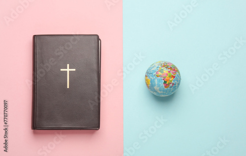 Bible book with globe on a pink blue background. Christian religion