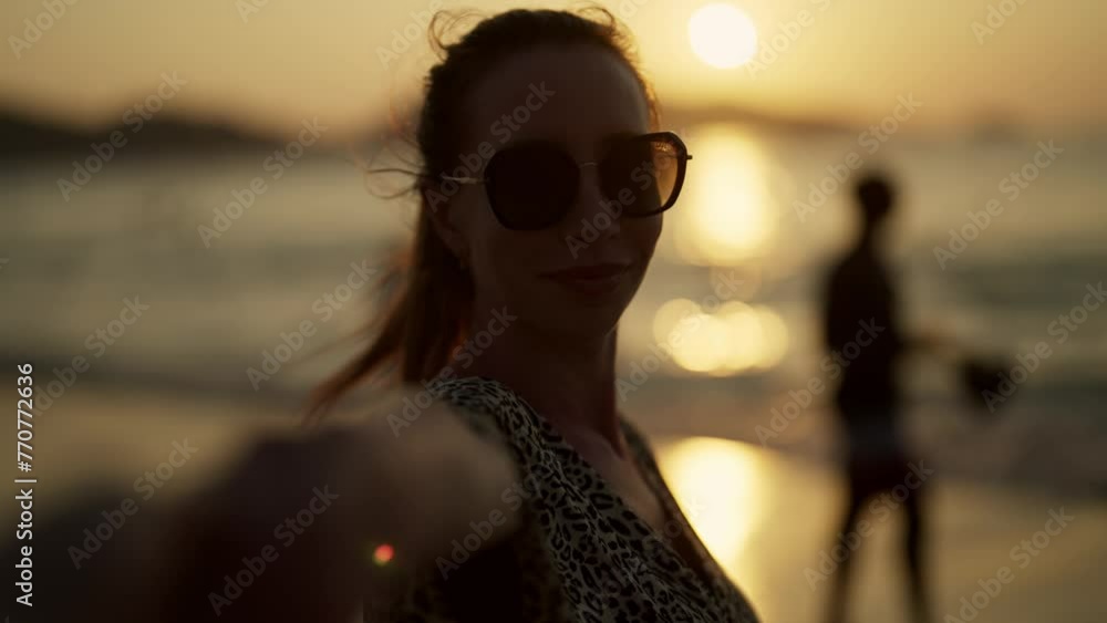 Young woman enjoying the sunset at sea. Close up happy long-haired girl travel blogger films herself on camera on nature sea ocean landscape at sunset, back view. Adventure trip, blogging concept. Young woman enjoying the sunset at sea. Close up happy long-haired girl travel blogger films herself on camera on nature sea ocean landscape at sunset, back view. Adventure trip, blogging concept.