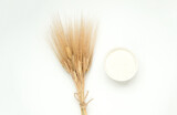 Spikelets of wheat and a bowl of flour on a white background
