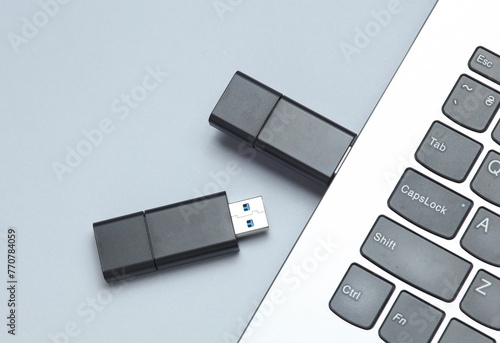 Fényképezés Two black USB flash drives and laptop keyboard gray background