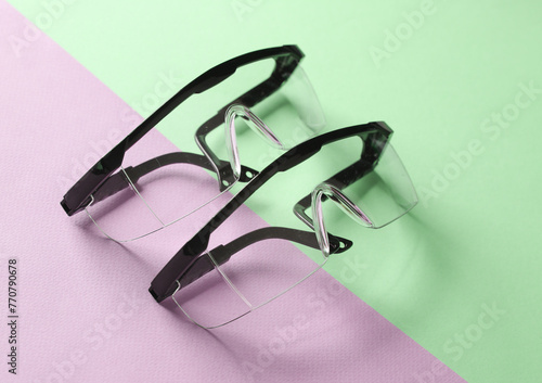 Two pairs of safety goggles on pink green background. Creative layout