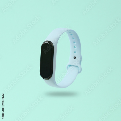 Modern smart bracelet levitating on a blue background with a shadow