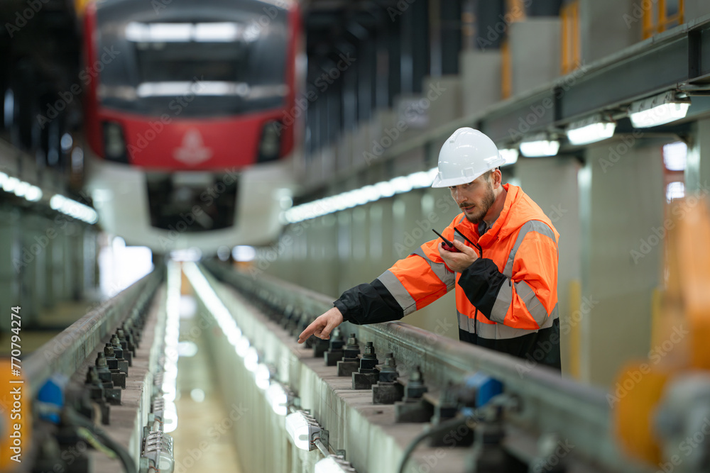Portrait of a young male technician using a walkie talkie working and standing in a skytrain repair station. Portrait of a young male technician using a walkie talkie working and standing in a skytrain repair station.