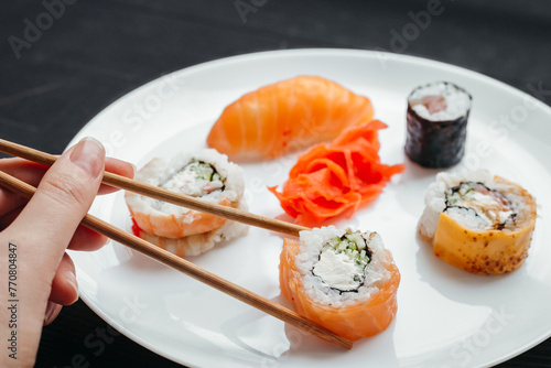 Different types of sushi rolls on white plates on black background top view