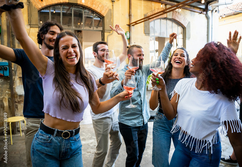 Group of friends have fun at a party dancing and joking while drinking wine and celebrating on a summer day