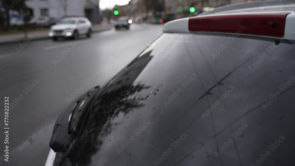 car exterior on the background of a city road. rear window of a car with bird droppings in the foreground. in the background a city road with passing cars out of focus on a cloudy rainy day. car exterior on the background of a city road. rear window of a car with bird droppings in the foreground. in the background a city road with passing cars out of focus on a cloudy rainy day.
