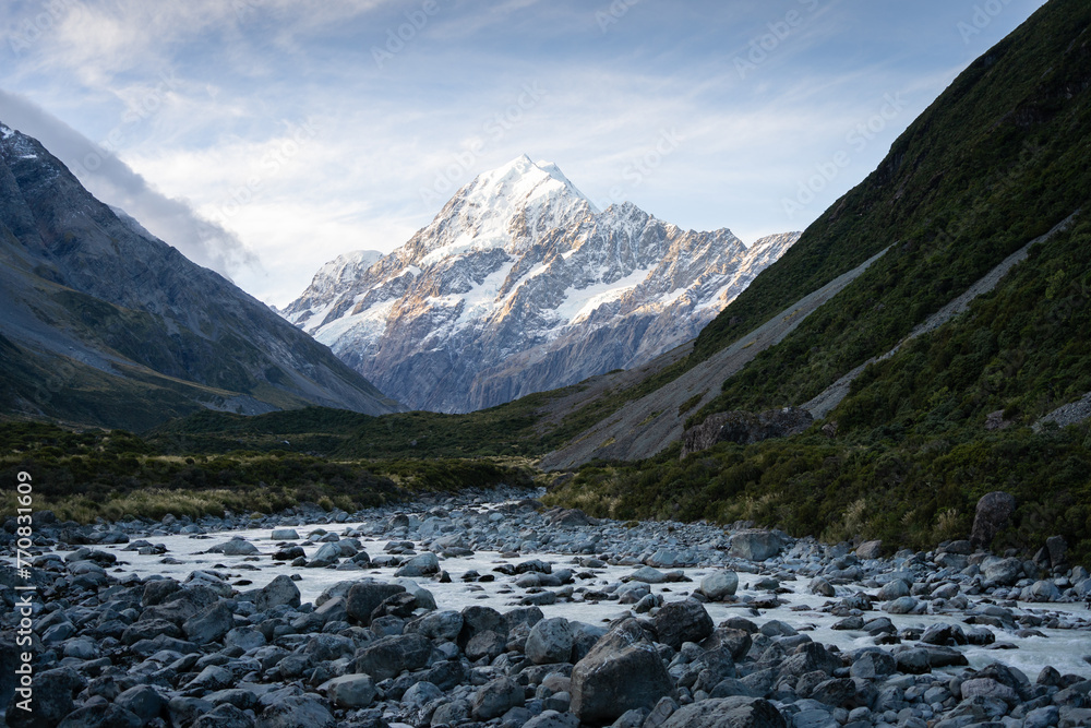 Alpine valley with glacial river flowing through and prominent peak in backdrop during sunset,Aoraki