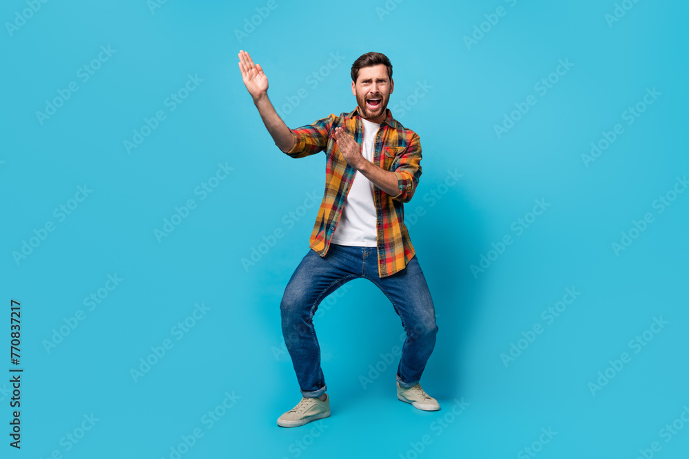 Full length photo of nice young guy hands karate pose frightened dressed stylish checkered garment isolated on blue color background