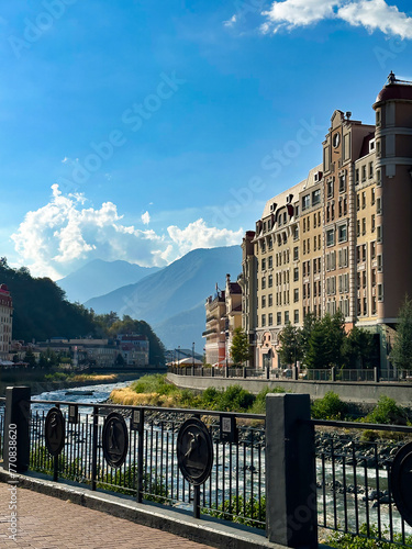 Sunny panorama of Rosa Khutor, Sochi, showing the idyllic mix of Alpine architecture and the rushing river in the Caucasus photo