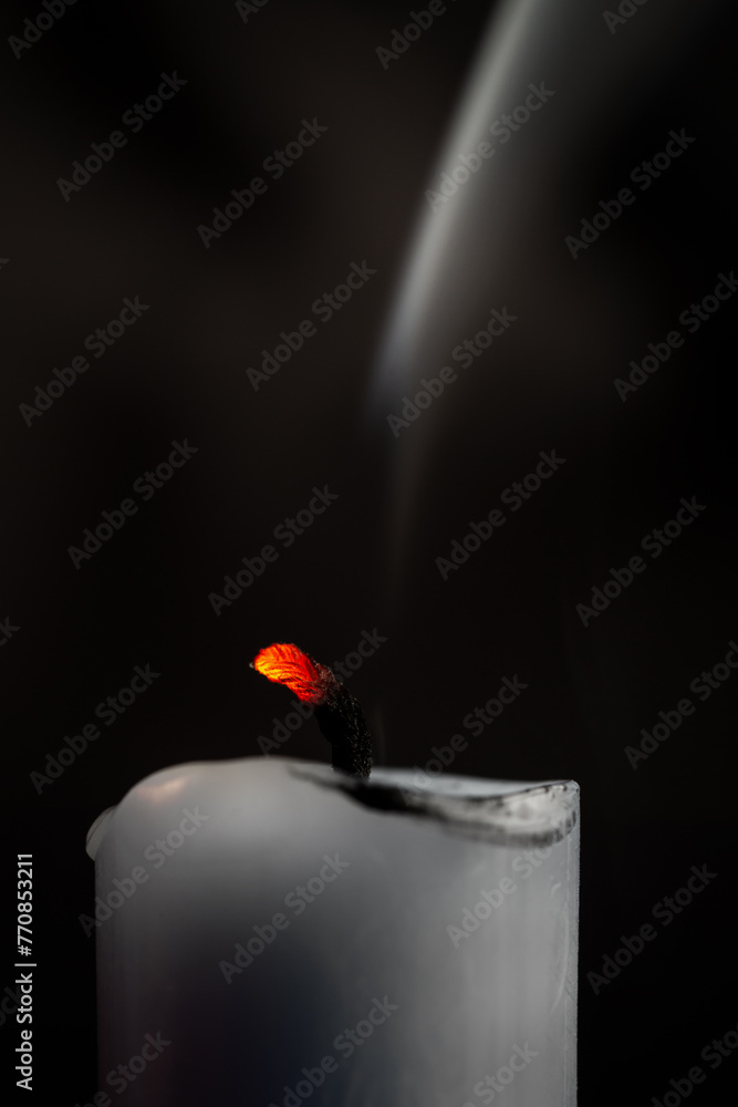 Glühender Kerzendocht mit Rauch von vergangenem Feuer vor dunklem Hintergrund - obrazy, fototapety, plakaty 