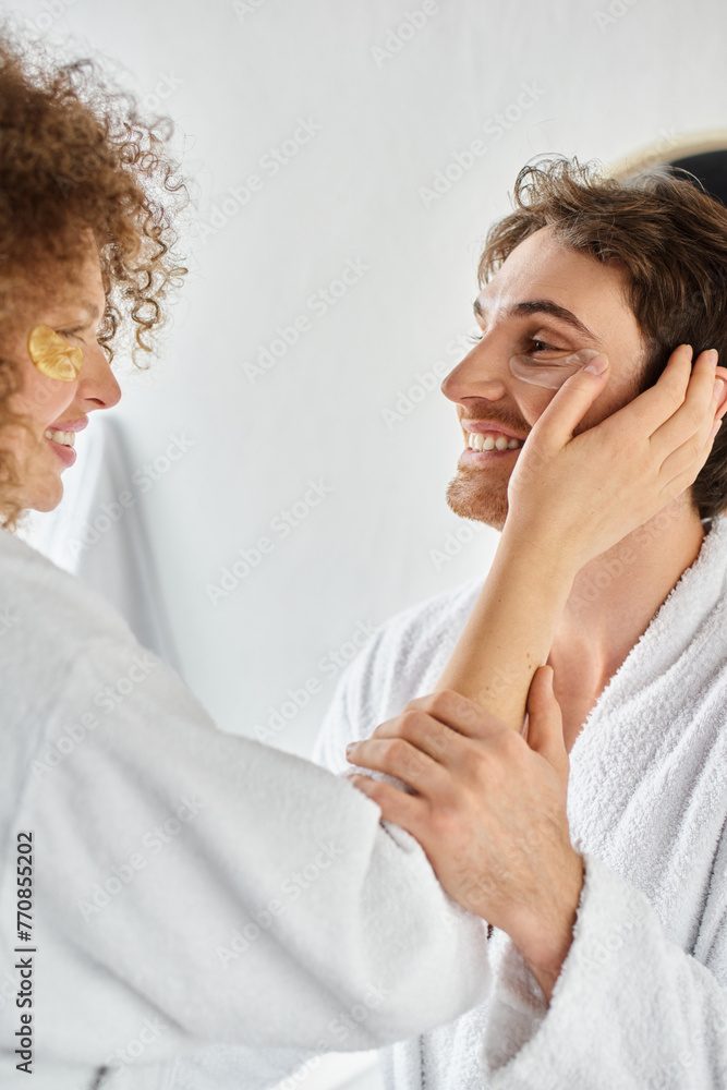 Side view portrait of couple with eye patches hugging in bathroom and smiling, bonding Side view portrait of couple with eye patches hugging in bathroom and smiling, bonding