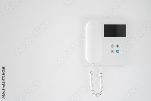 Modern intercom system with handset on white wall background in apartment