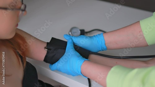 The doctor measures the girl's blood pressure in the clinic.