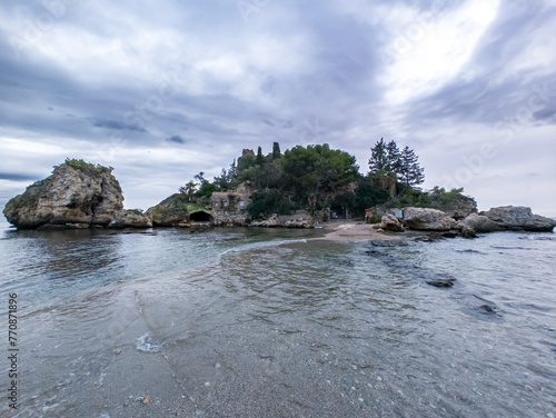 Panoramic view of beautiful Isola Bella, small island near Taormina, Sicily, Italy. Narrow path connects island to mainland Taormina beach surrounded by azure waters of Ionian Sea.