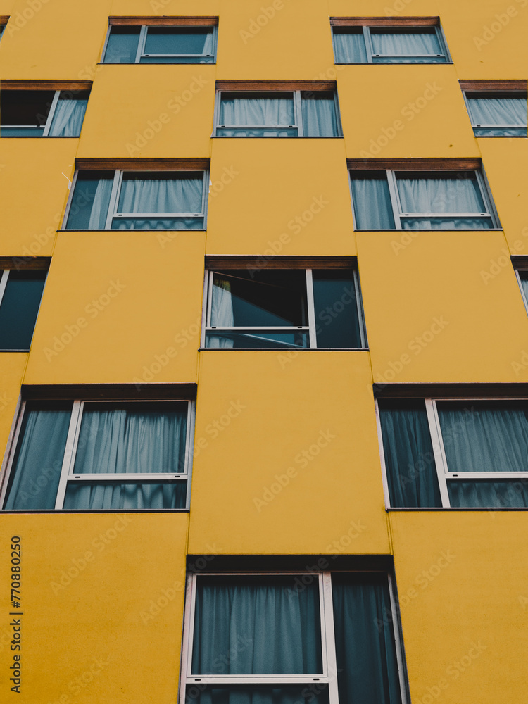 Naklejka premium symmetrical residential yellow building close shot low angle in San Sebastian on a cloudy day