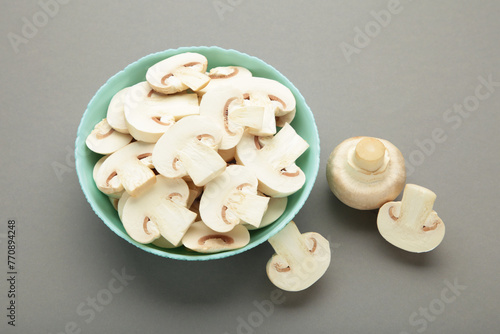 Fresh white champignon mushrooms on mint plate on grey background.