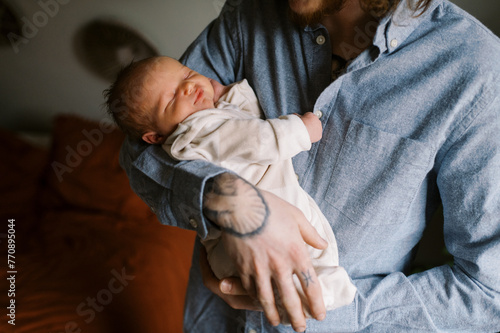 father holding newborn baby boy in arms at home photo