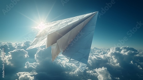   A paper plane soars in the sky, above clouds, as sunlight graces its wingtop photo