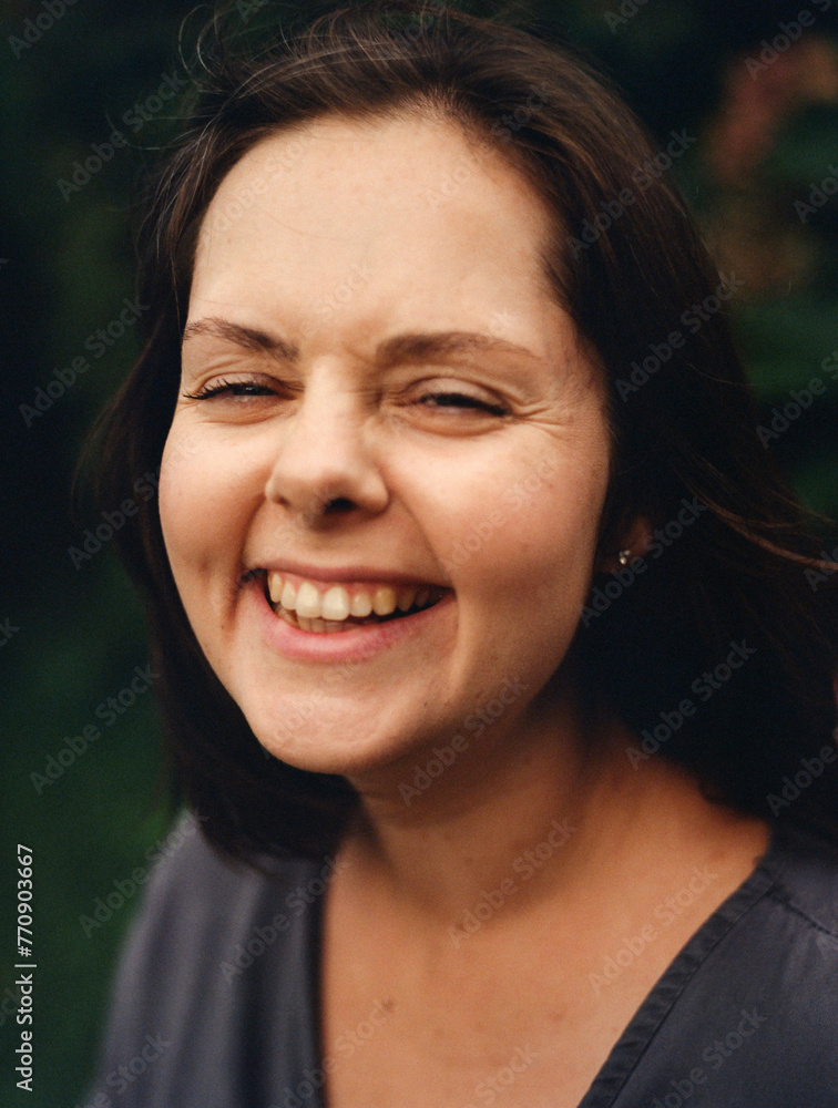 Woman Smiling Against a Natural Green Background Woman Smiling Against a Natural Green Background