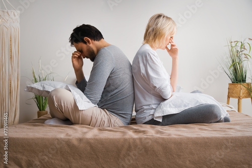 Unhappy sad couple, bearded man, woman, husband and wife sit on home bed, turned away back to back from each other. Unlove crisis, sexual problem issues, relationship conflict, divorce - concept image