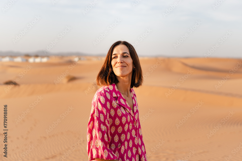A smiling woman standing in a desert landscape, looking happy. A smiling woman standing in a desert landscape, looking happy.