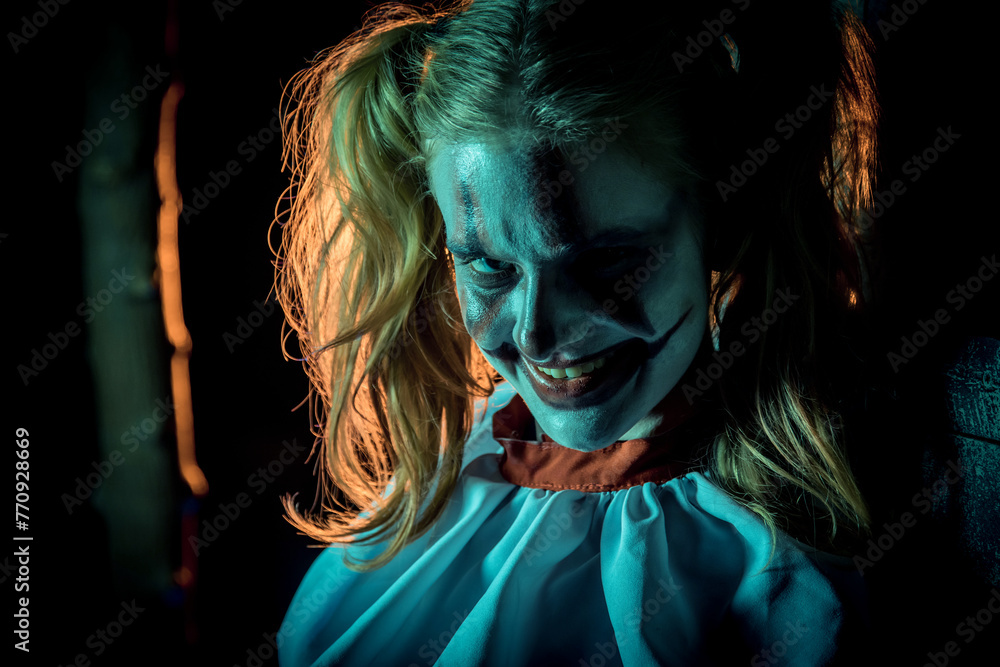 Halloween horrors. A scary laughing clown girl, dressed in a circus dress.