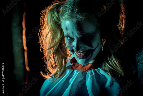 Halloween horrors. A scary laughing clown girl, dressed in a circus dress.