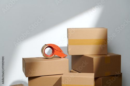 tape dispenser and stack cardboard boxes on floor near white wall photo