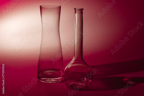 Close-up of two decorative glass vases on red background with backlit