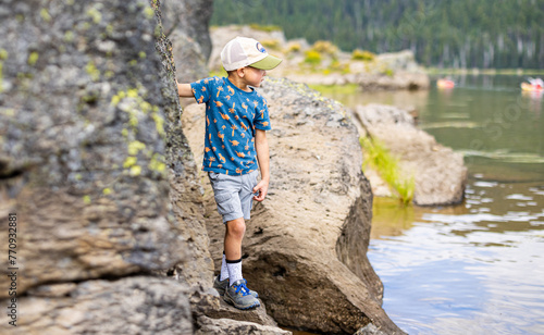 child exploring on rocks near a lake 