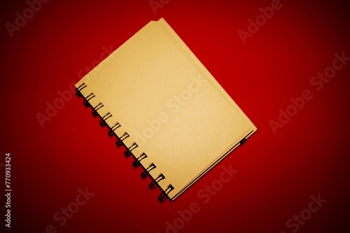 notepad with leaves, pages produced naturally with recycled materials, on a red background
