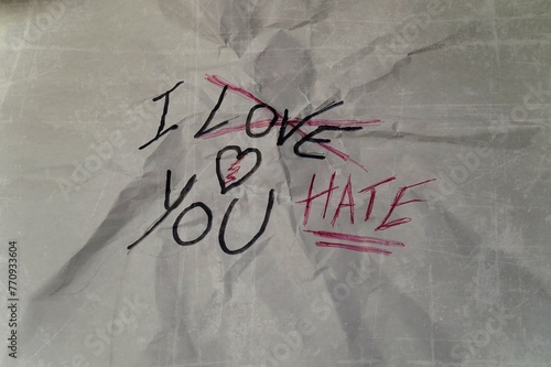 crumpled sheet of paper, with the writing, "I love you", crossed out and replaced with "I hate you", concept of the thin line that separates love from hate, in relationships
