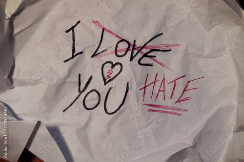 crumpled sheet of paper, with the writing, "I love you", crossed out and replaced with "I hate you", concept of the thin line that separates love from hate, in relationships
