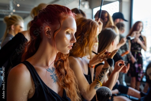 A group of women standing next to each other backstage at a fashion show, getting ready with makeup artists and stylists