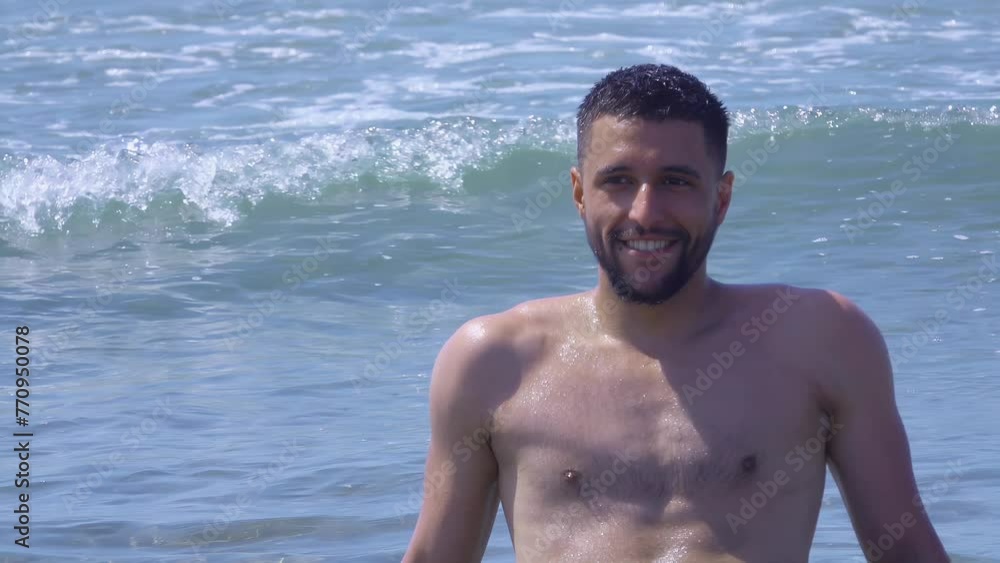 Young handsome man is sitting on the shore in the waves and enjoys a sea vacation Young handsome man is sitting on the shore in the waves and enjoys a sea vacation