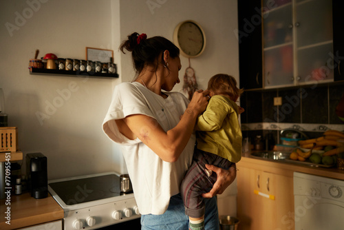 Mother holds a kid in the kitchen photo