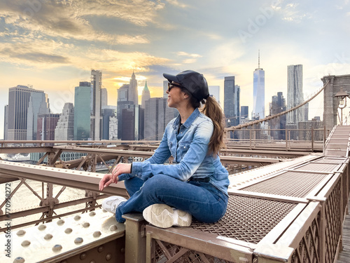 Woman overlooking Manhattan skyline from Brooklyn Bridge