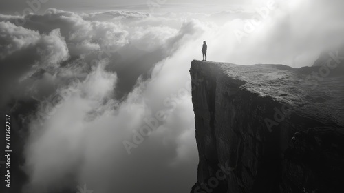A person stands on a cliff overlooking a mountain. The sky is cloudy and the sun is shining through the clouds. The scene is peaceful and serene, with the person standing alone