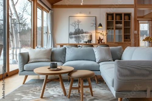 The living room boasts a sofa with wooden legs and armrests crafted from solid wood, featuring blue fabric seats placed atop a light gray carpet on the floor photo