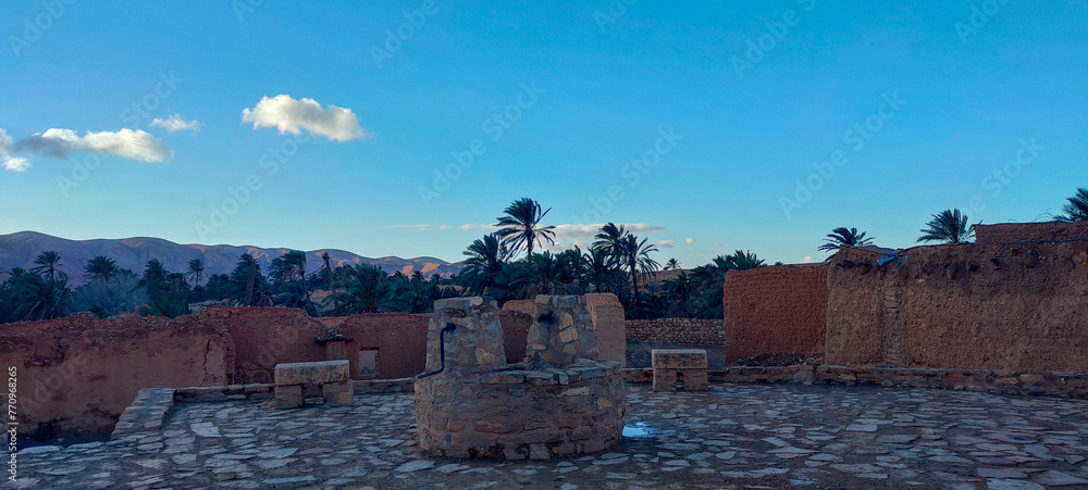Old clay buildings among palm trees in the village Dechra Hamra, the town of El Kantara. Biskra. Algeria